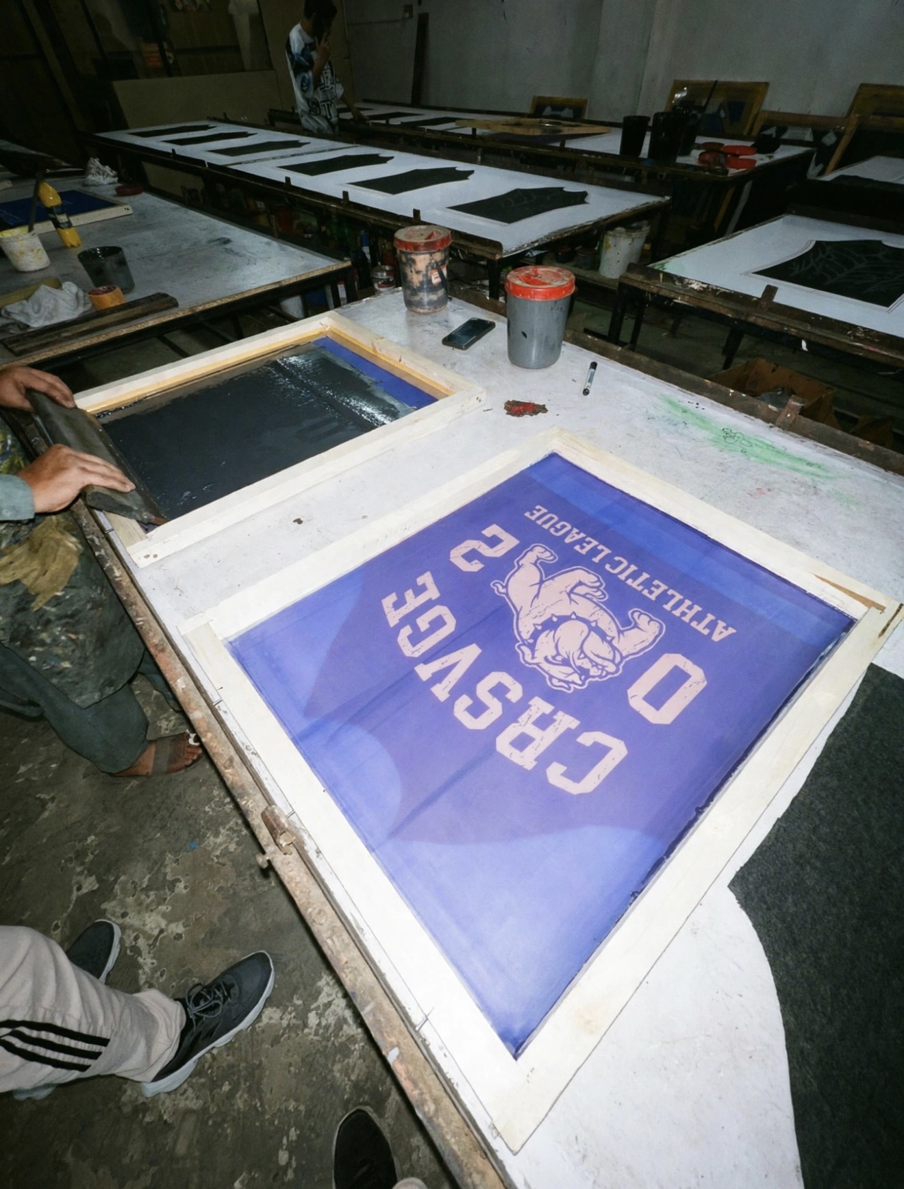 Silk-screening the Athletic League bulldog print on the production table