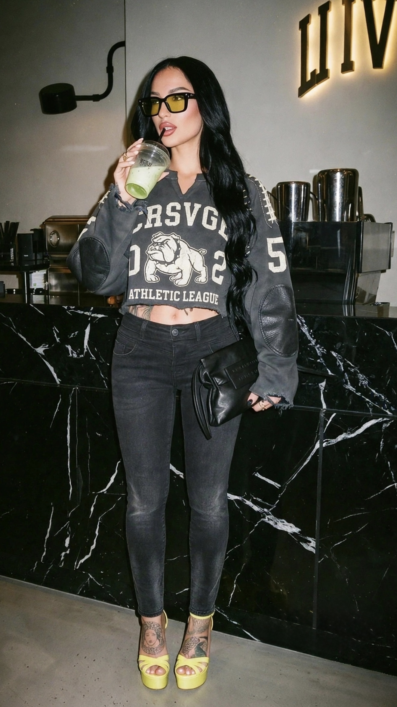 Full-body model at a black marble counter in the Athletic League bulldog crewneck and platform heels